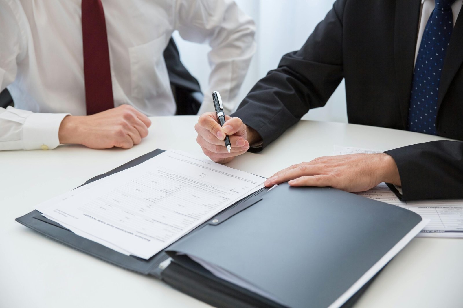 Two professionals signing a contract at a business meeting in an office.